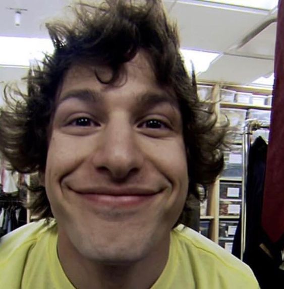 a man with curly hair smiling at the camera