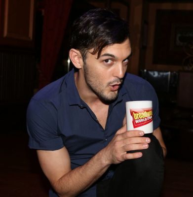 a man holding a coffee mug in his hand and looking at the camera with an intense look on his face