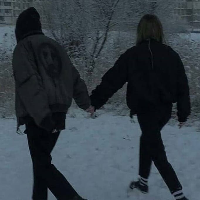 two people walking in the snow holding hands