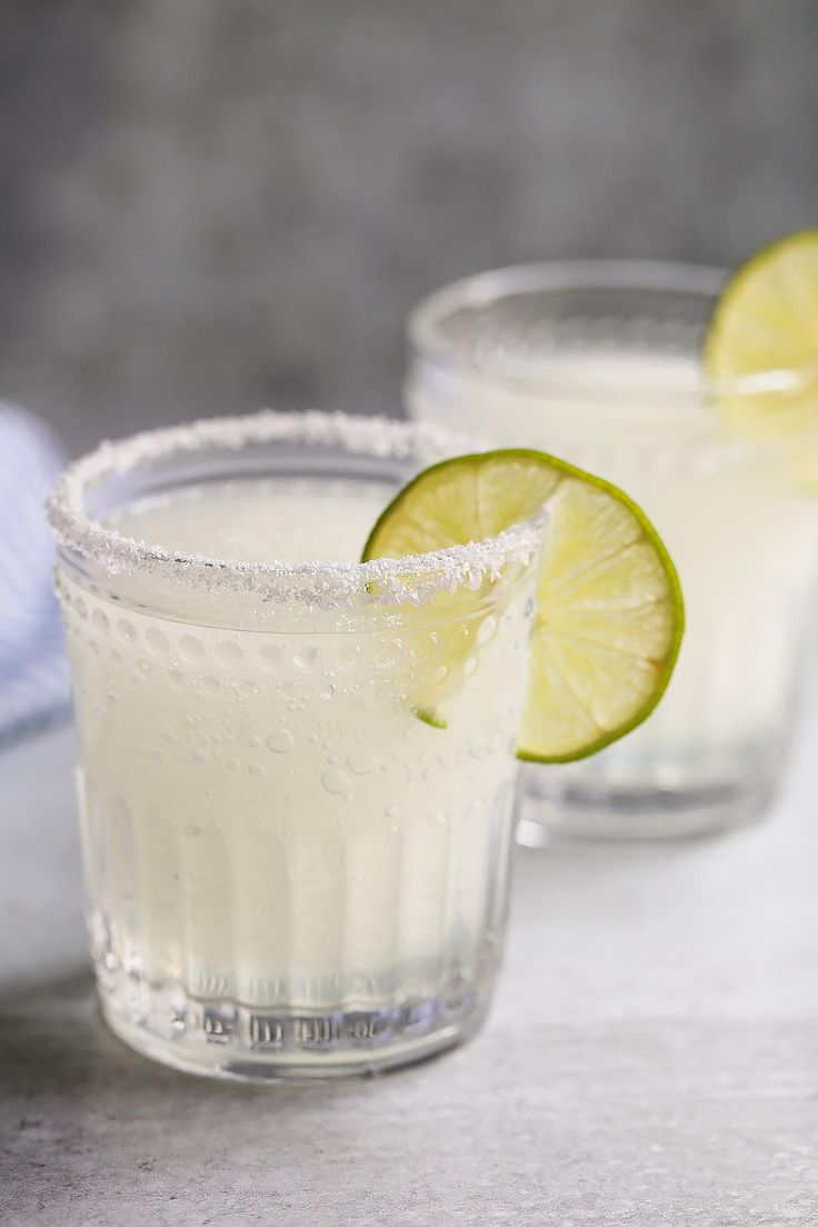 two glasses filled with lemonade and lime slices