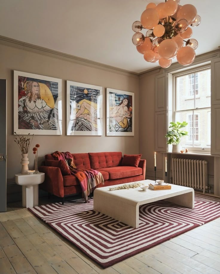 a living room with red couches and pictures on the wall above it's coffee table