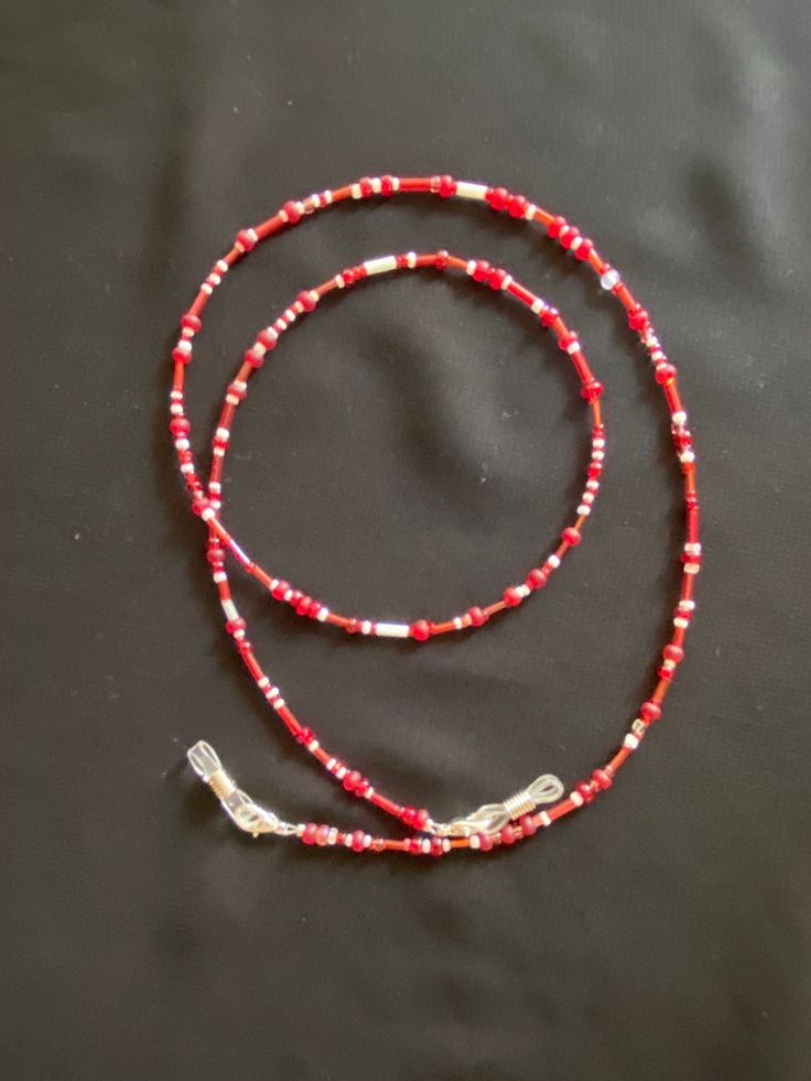 Hand-beaded eyeglass chain.  27" in length.  Tipped with silicone eyeglass holders attached with lobster clips.  Made with a variety of glass beads in reds and whites. White Glasses Chains With Lobster Clasp And Round Beads, Red Adjustable Necklaces With Lobster Clasp, Red Adjustable Necklace With Lobster Clasp, Adjustable Red Necklace With Lobster Clasp, Adjustable Red Beaded Necklace With Lobster Clasp, Adjustable Single Strand Red Beads, Adjustable Red Beaded Necklace For Beach, Red Glass Jewelry For Beach, Red Beaded Glasses Chains As Gift