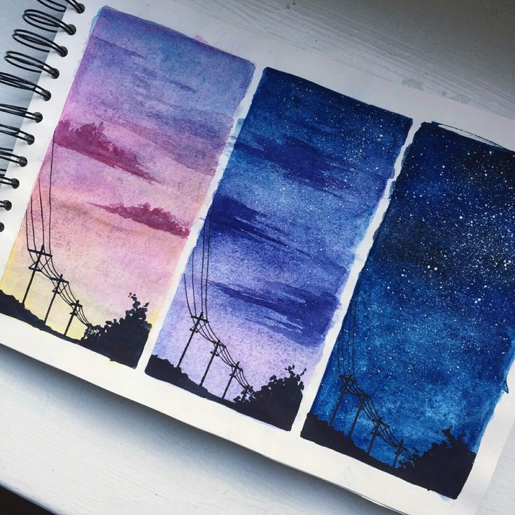 four different colored watercolors are shown on a notebook with the sky in the background