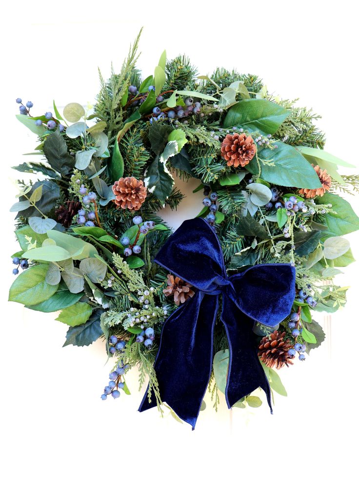 a wreath with blue velvet bow and pine cones