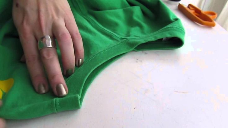 a woman's hand on top of a green t - shirt with scissors in the background