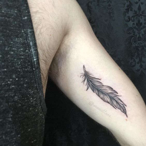 a man's arm with a feather tattoo on the left side of his arm