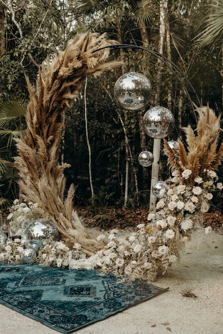 an outdoor wedding arch decorated with flowers and disco balls