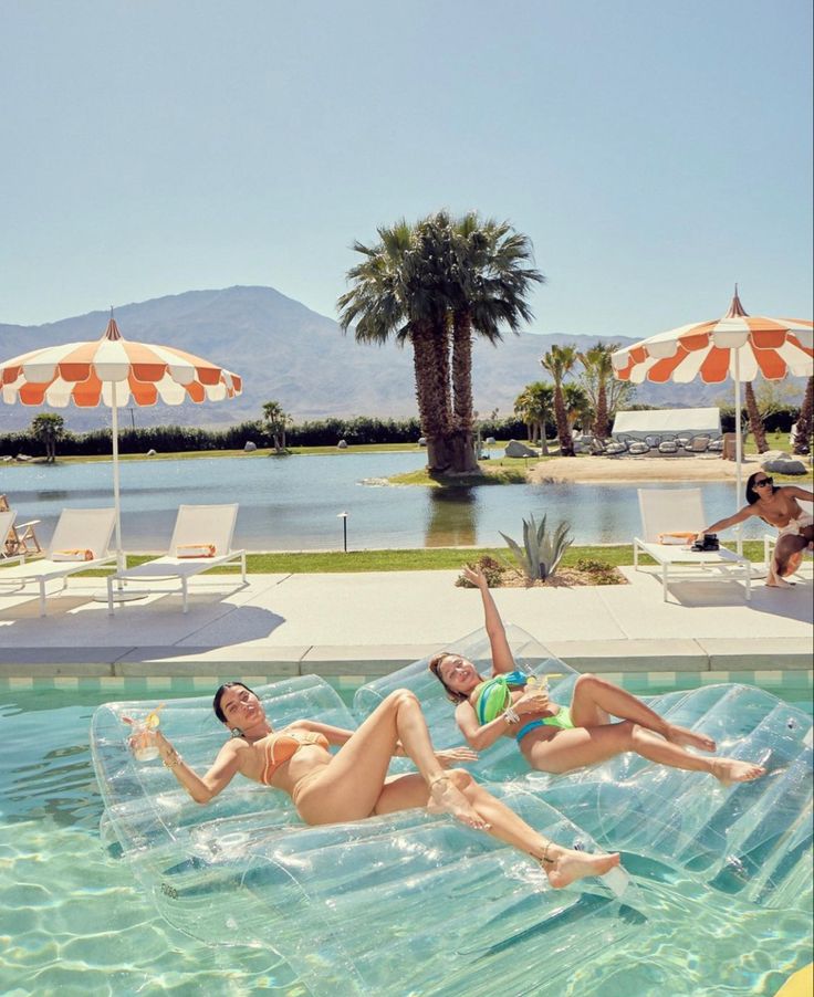 two women in bikinis are floating on an inflatable pool