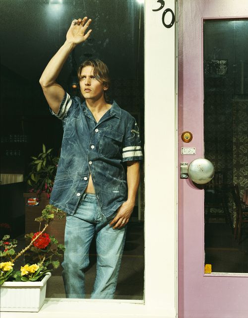 a man standing in front of a pink door with his hand up to the side