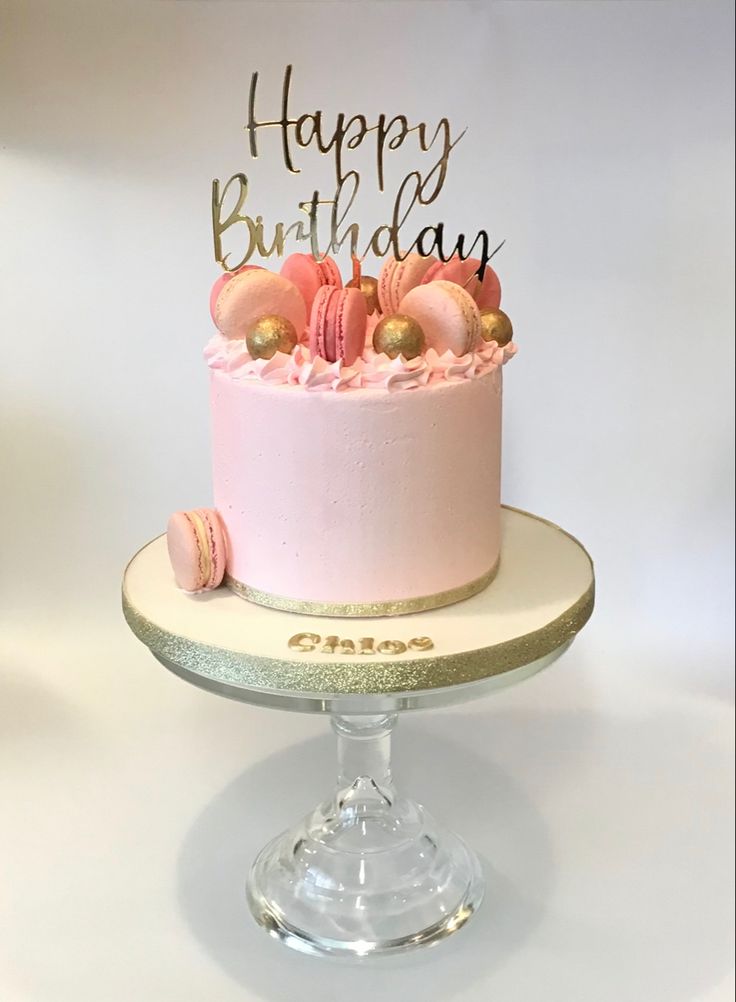 a birthday cake with pink frosting and gold decorations