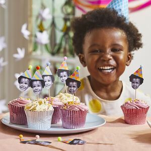 a young child sitting at a table with cupcakes