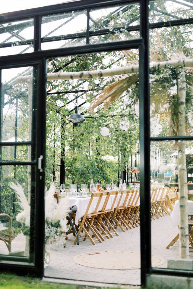 an outdoor dining area with tables and chairs in front of large glass windows that look out onto the trees