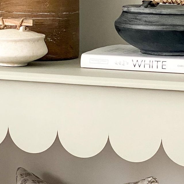 a white shelf topped with books and two vases on top of eachother