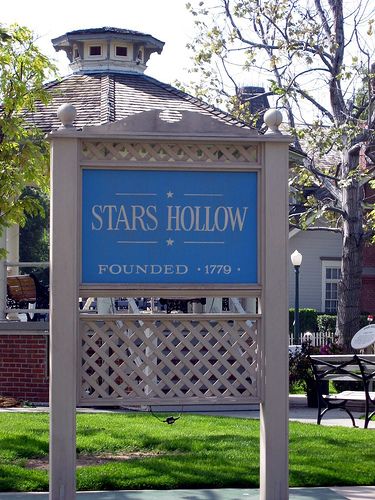 a blue sign that says stars hollow is in front of a building with trees and lawn furniture