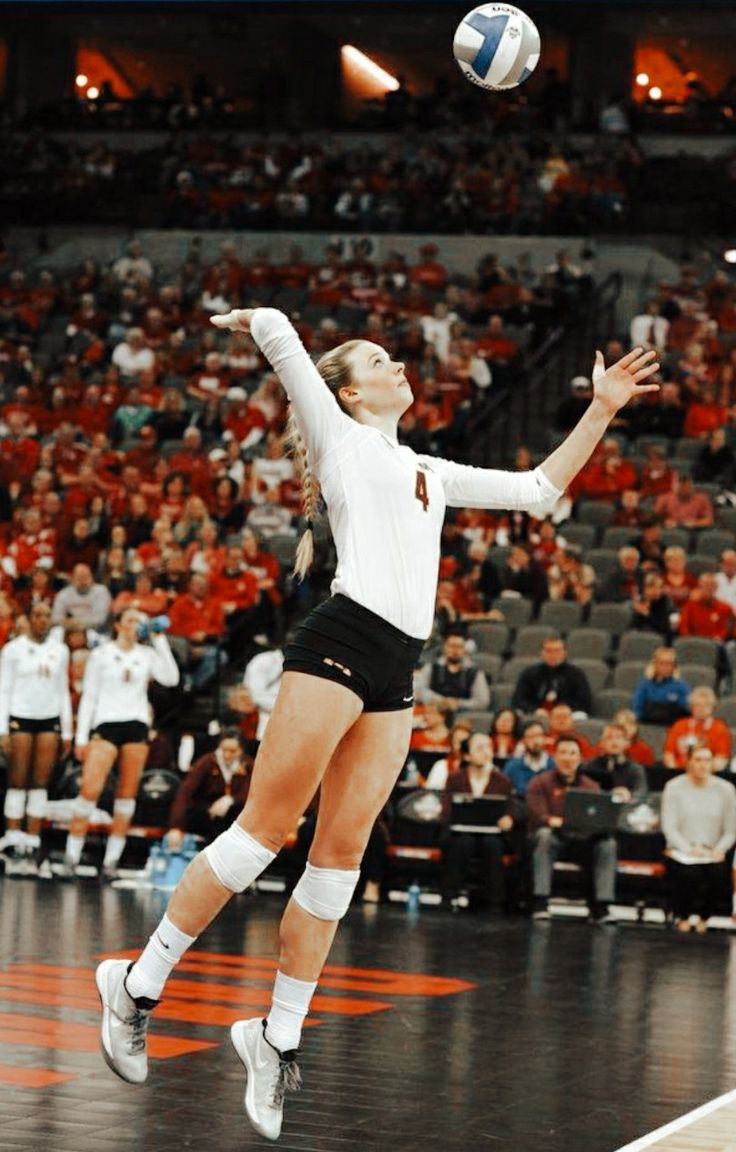 a female volleyball player jumping up to hit the ball