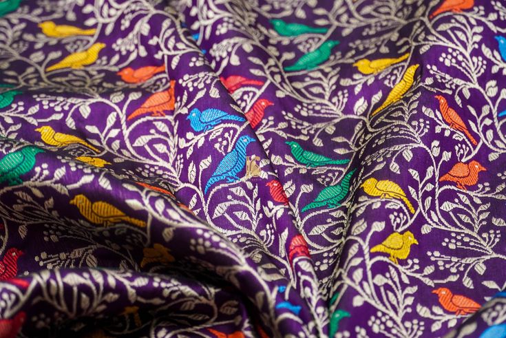 the fabric has birds on it and is purple with multicolored leaves in different colors