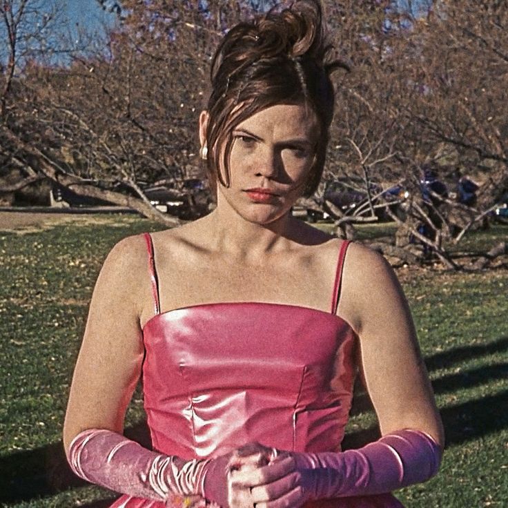 a woman in a pink dress sitting on the grass