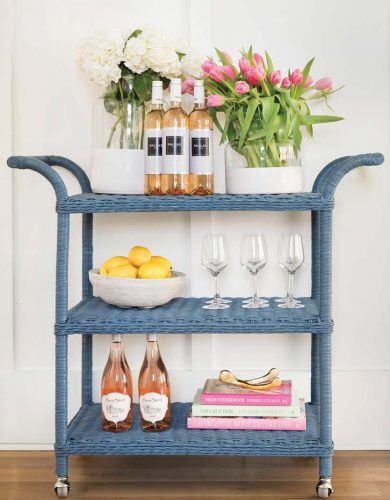 a blue shelf with wine glasses, lemons and bottles on it next to flowers