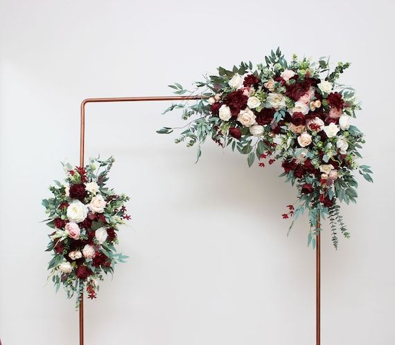 two floral arrangements are arranged on the wall for an artistic wedding photo shoot in front of a white backdrop