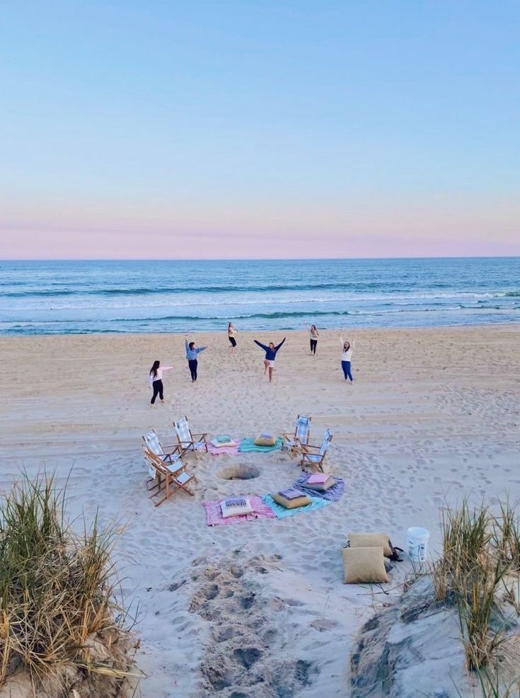 people doing yoga on the beach with their arms in the air