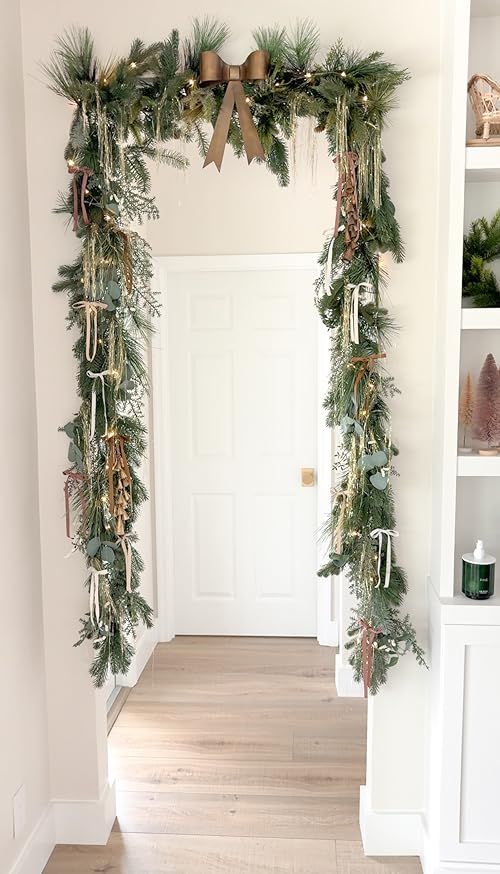 a hallway decorated for christmas with greenery and garland on the door way to the front door