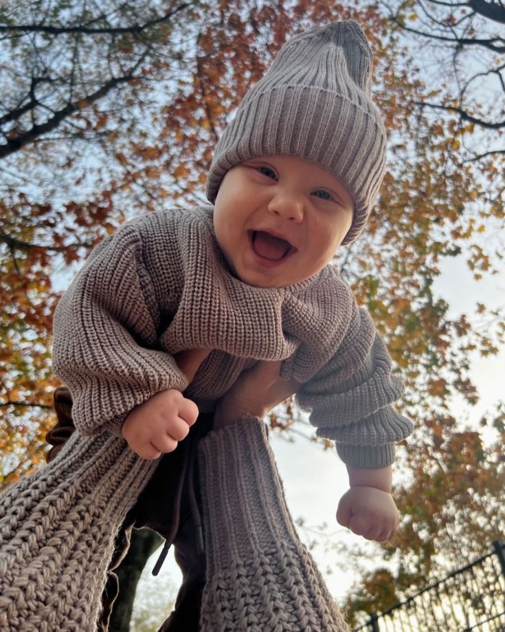 a baby wearing a knitted sweater and hat