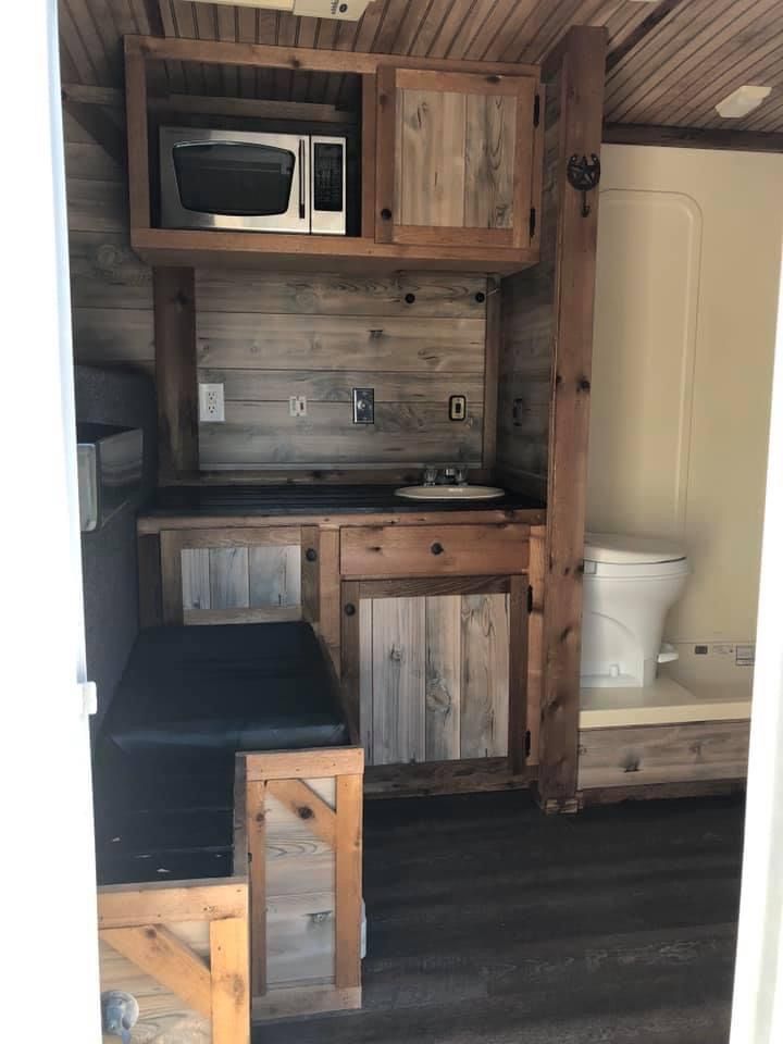 a small kitchen with wooden cabinets and black counter tops, along with a white toilet in the corner