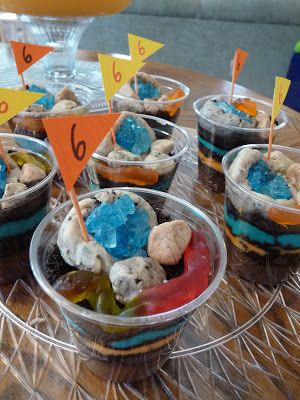 cupcakes in plastic containers with flags on them sitting on a clear plate, ready to be eaten