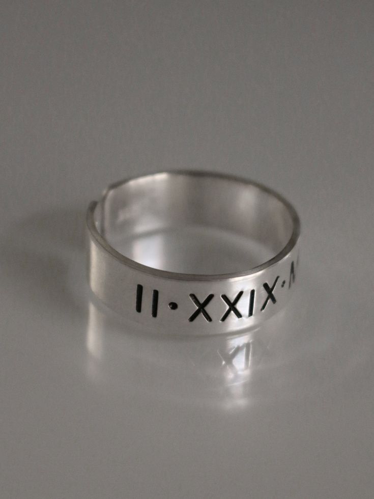 This Roman numeral ring is the perfect piece of personalized jewelry for anniversaries, promise rings and more. Crafted from quality materials, this date ring can be inscribed with custom Roman numerals for a unique piece of jewelry. A great gift for your loved one to commemorate a special occasion. Product Details: Materials: Aluminum, Sterling Silver, Fine Silver, 14k Gold Filled Color: Silver, Gold, Rose Gold Size: 6mm You will receive one hand-stamped ring filled with no enamel finish. Hand Stamped Adjustable Jewelry For Anniversary, Adjustable Hand Stamped Jewelry For Anniversary, Modern Adjustable Initial Ring For Anniversary, Silver Hand Stamped Rings For Anniversary, Hand Stamped Elegant Promise Ring, Hand Stamped Silver Rings For Anniversary, Hand Stamped Ring For Anniversary, Classic Hand Stamped Rings For Anniversary, Minimalist Hand Stamped Engraved Ring For Anniversary