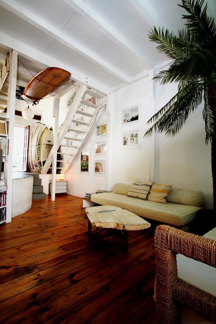 a living room filled with furniture and a tree in the corner next to a stair case