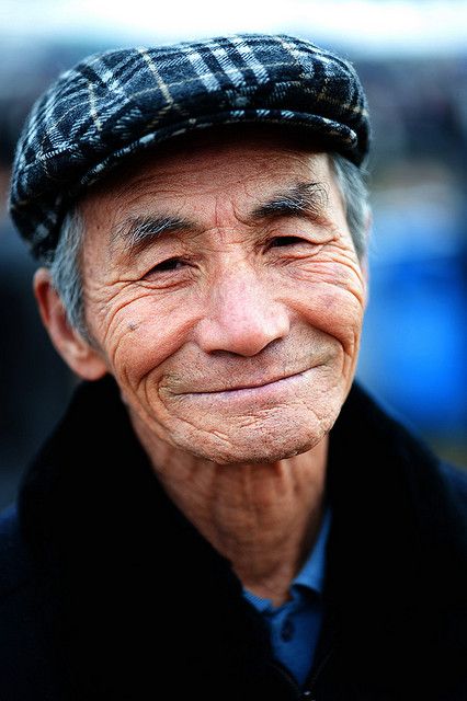 an older man wearing a hat and smiling at the camera with his eyes wide open