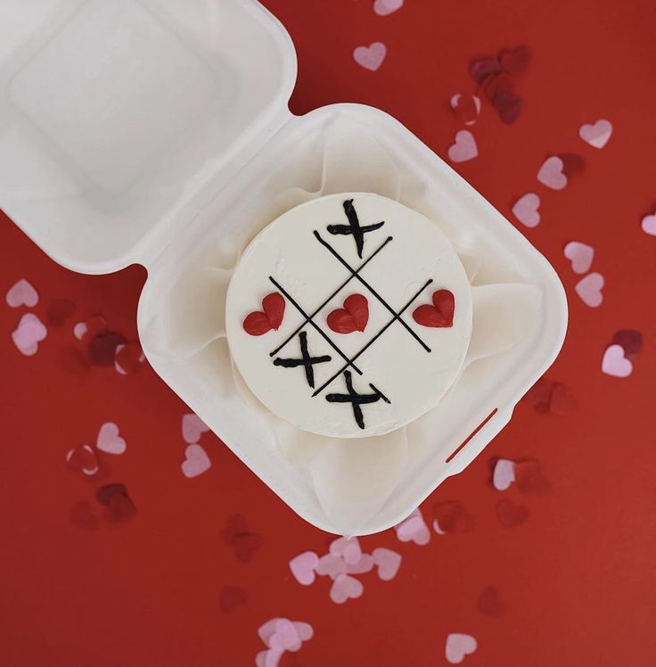 a cake in a plastic container with hearts on it