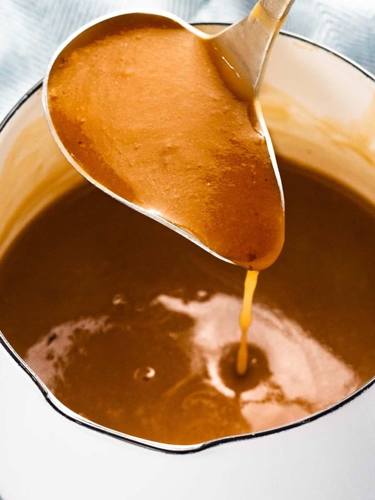 a spoon pouring caramel sauce into a pot