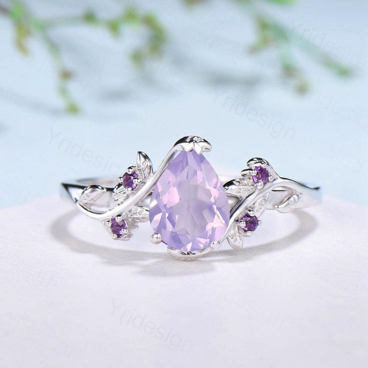 an oval shaped amethorate ring with leaves around the band and purple stones on each side