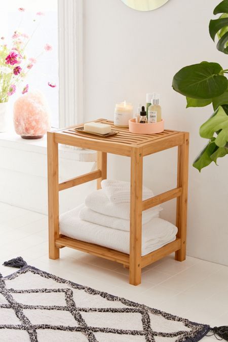 a wooden table with white towels on it in front of a mirror and potted plant