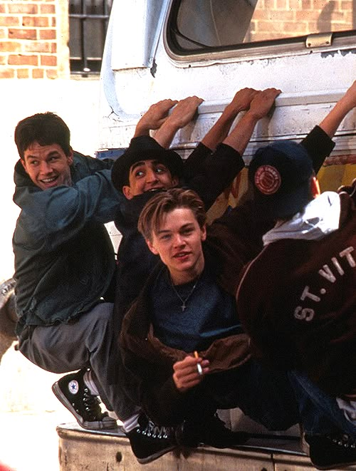 several young men climbing up the side of a van with their hands in the air