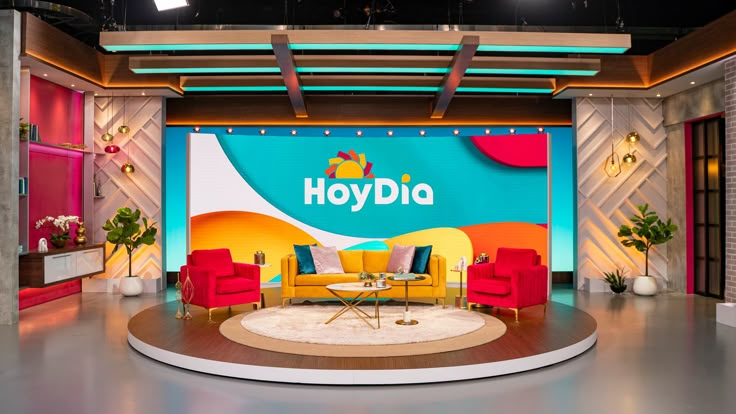 a television set with chairs and a table in front of a large sign that says hoyddia