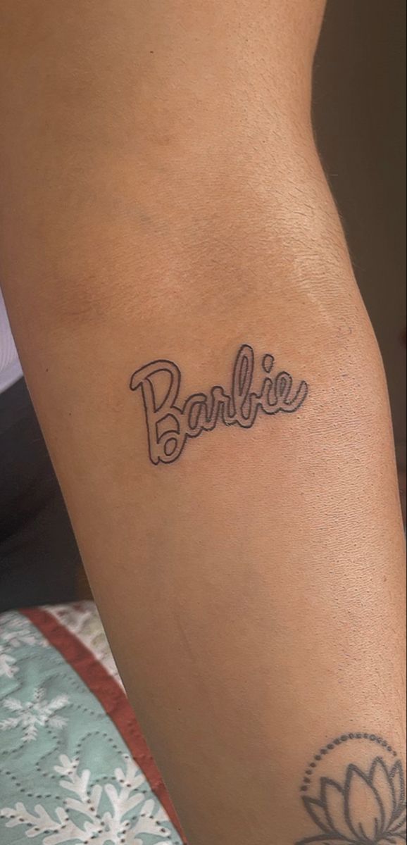 a woman's leg with the word barbie tattooed on her lower arm and foot