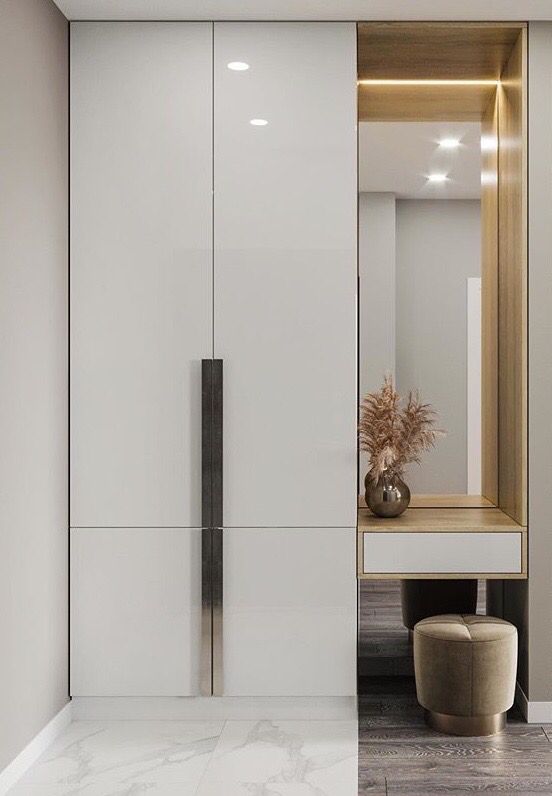 a white closet with a mirror, stool and vase on the floor in front of it