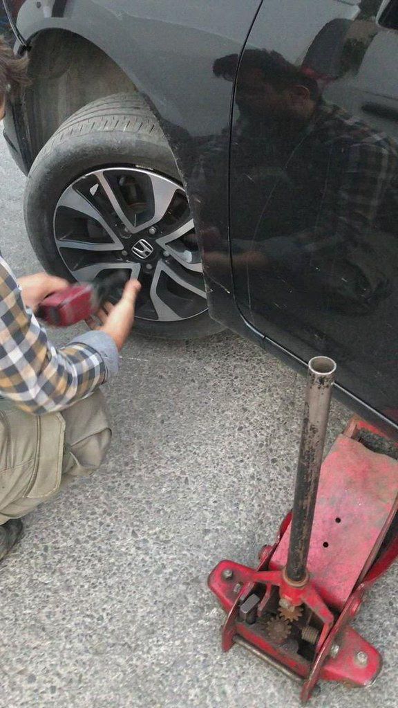 a man is working on the tire of a car with a jack wrench in front of it