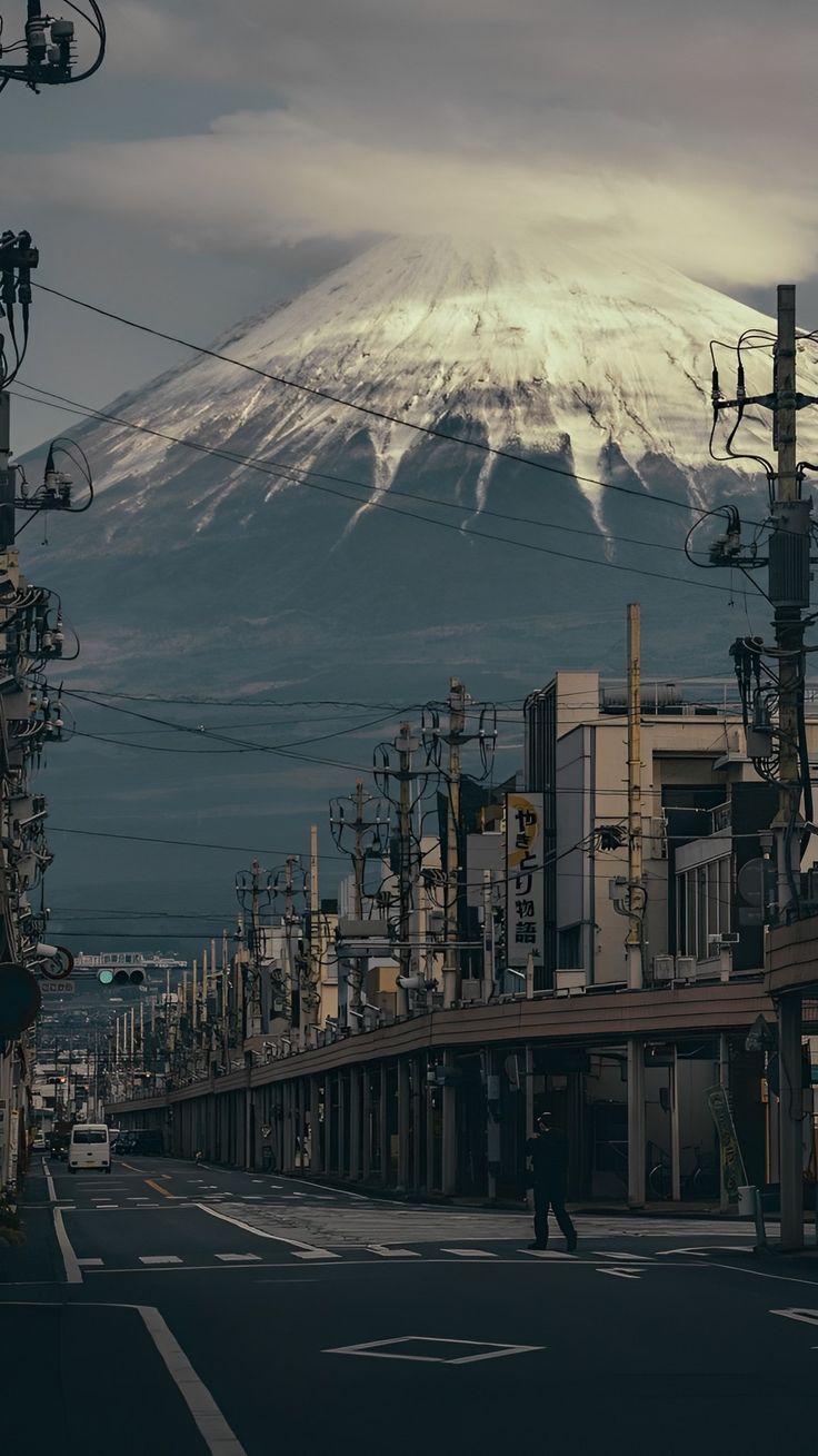 a city street with power lines and telephone poles in front of a snow covered mountain