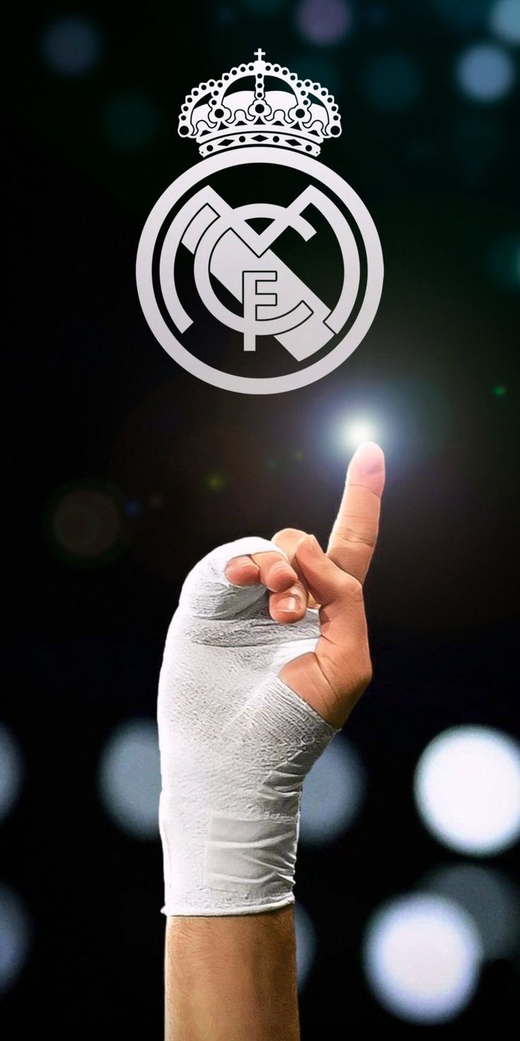 a hand holding up a finger with the real madrid logo on it