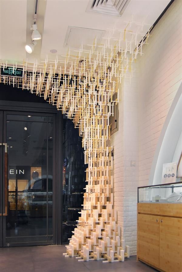 an art installation made out of wood sticks in front of a storefront door with the doors open