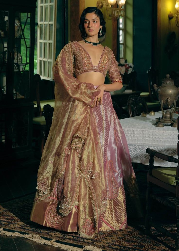 Indulge in timeless luxury with this purple silk kalidar lehenga set, showcasing Jharokha-inspired panels and intricate paisley embroidery in zari and zardozi. The ensemble is elevated with dabka, sequins, pearls, and gota detailing. Paired with a heavily embroidered blouse featuring pearl tassels and a shimmering tissue dupatta adorned with sequin and pearl accents, this set offers an effortlessly graceful and refined silhouette. Lavender And Gold Lehenga, Light Purple Lehenga, Tissue Silk Lehenga, Diy Lehenga, Aditi Gupta, Tissue Lehenga, Tissue Dupatta, Pearl Tassels, Purple Lehenga