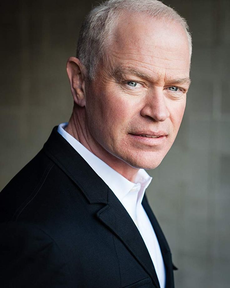 a man in a black suit and white shirt is looking at the camera with an intense look on his face