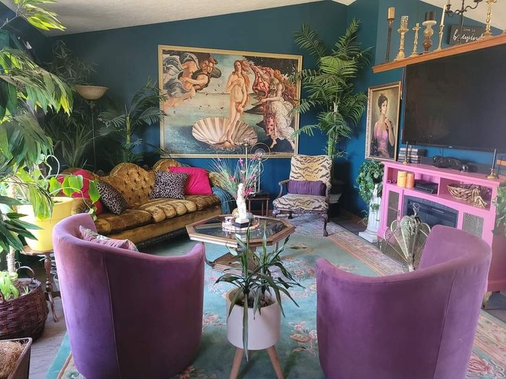 a living room filled with purple furniture and lots of greenery on the wall behind it