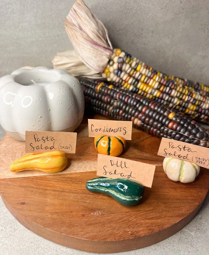 corn on the cob, pumpkins and other vegetables are arranged on a wooden board