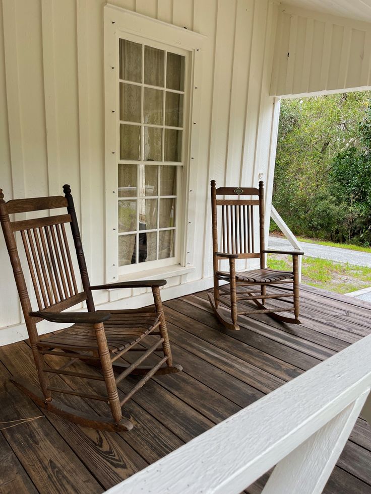 two wooden rocking chairs sitting on top of a porch