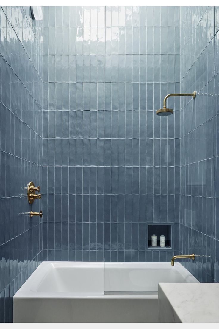 a bathroom with blue tile and gold fixtures