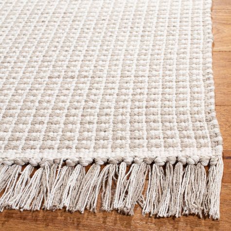 a white rug with tassels on top of wooden floor next to wood flooring